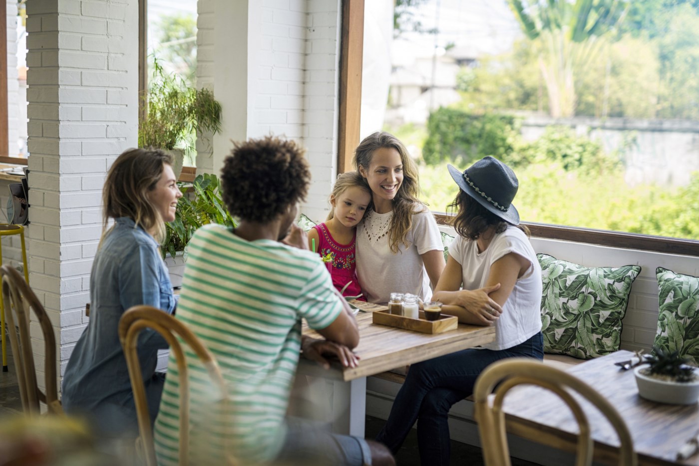 Smilande kvinner på kafé, snakkar saman.