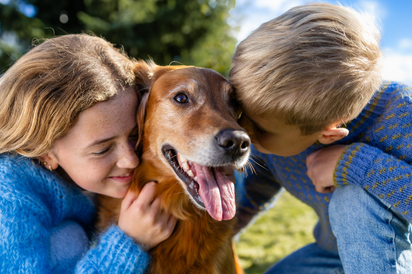 Jente og gut kosar med hunden mellom seg