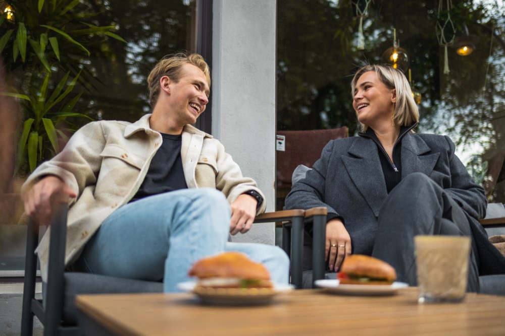 Ung mann og kvinne på kafé med mat og kaffi